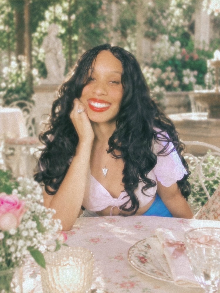 Genesis, founder of Ballet Core Method, smiling at a garden table